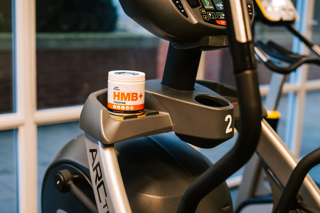 A tub of Blonyx HMB+ Creatine on a stationary bike