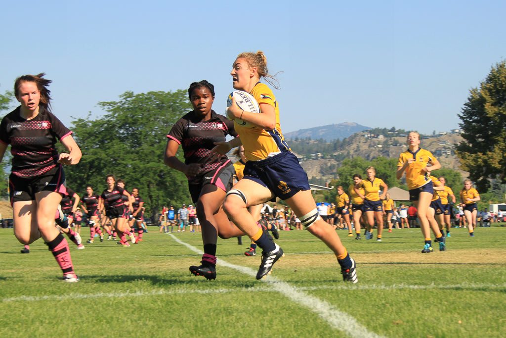 Female rugby player carrying the ball up the field