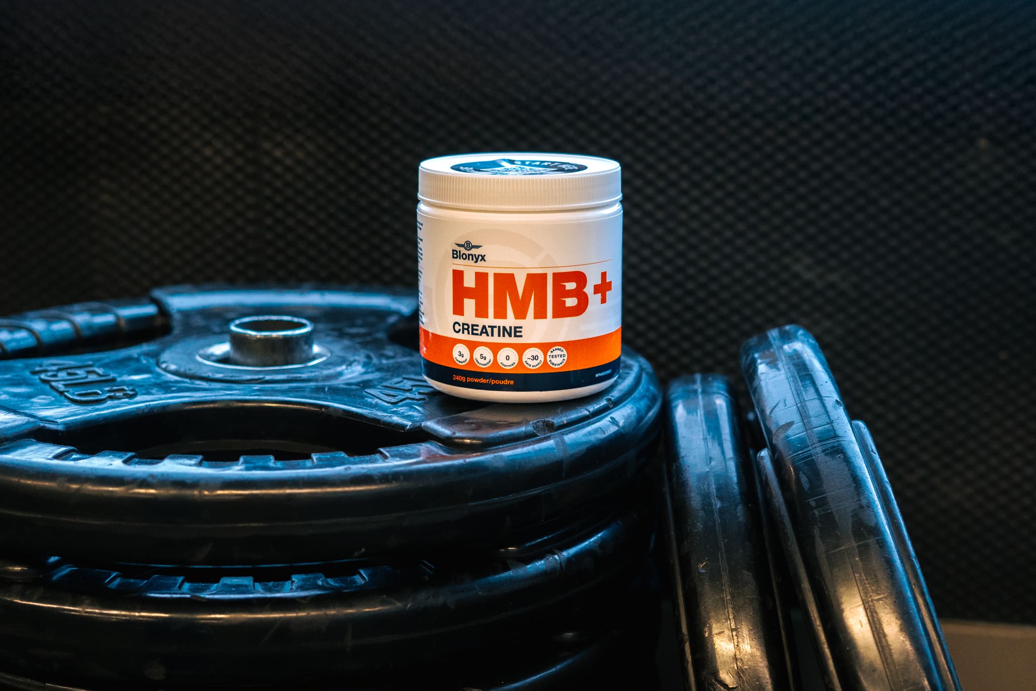 Blonyx HMB+ Creatine on a Stack of Weight Plates