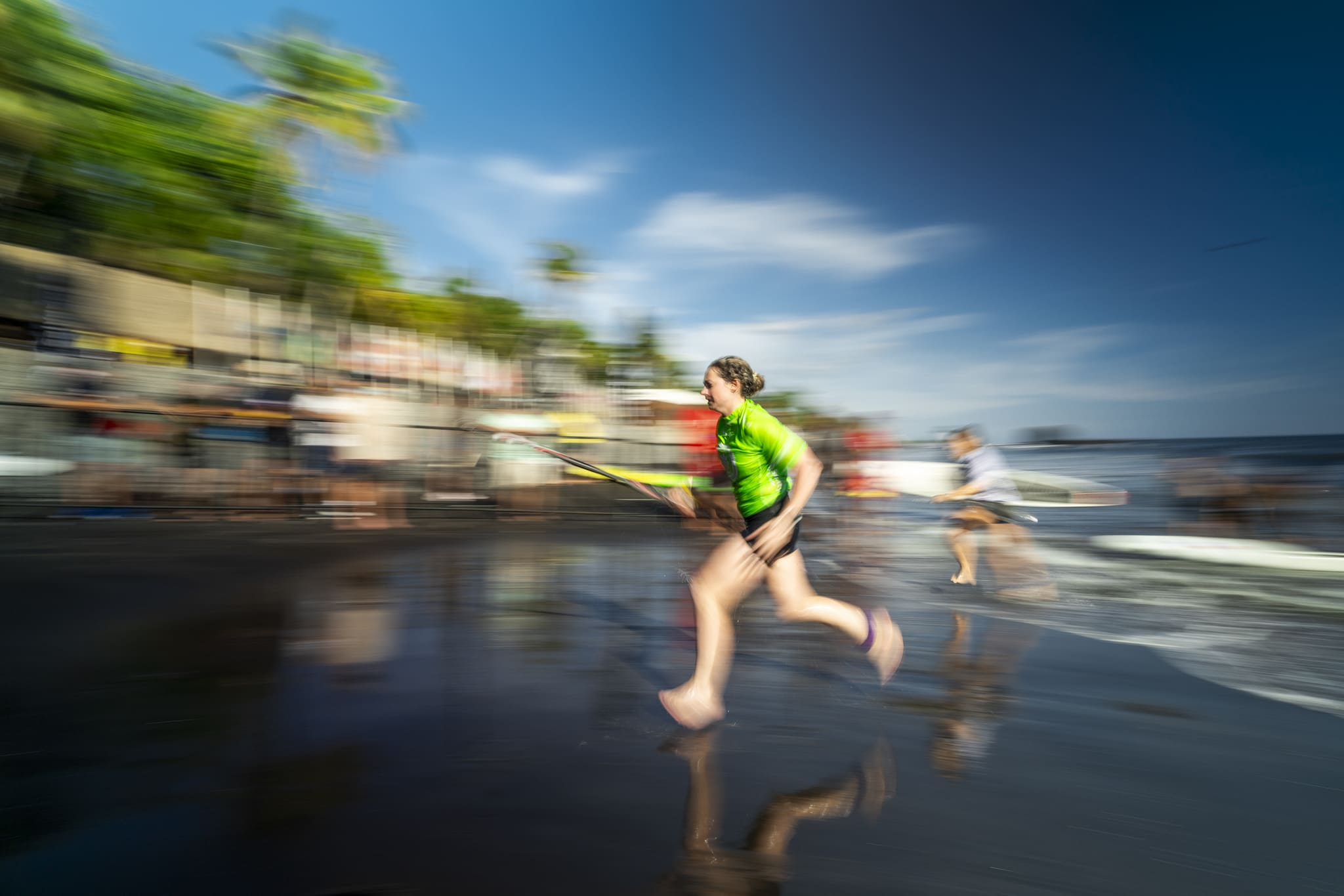 Caroline Cook races up a beach at the end of a SUP competition