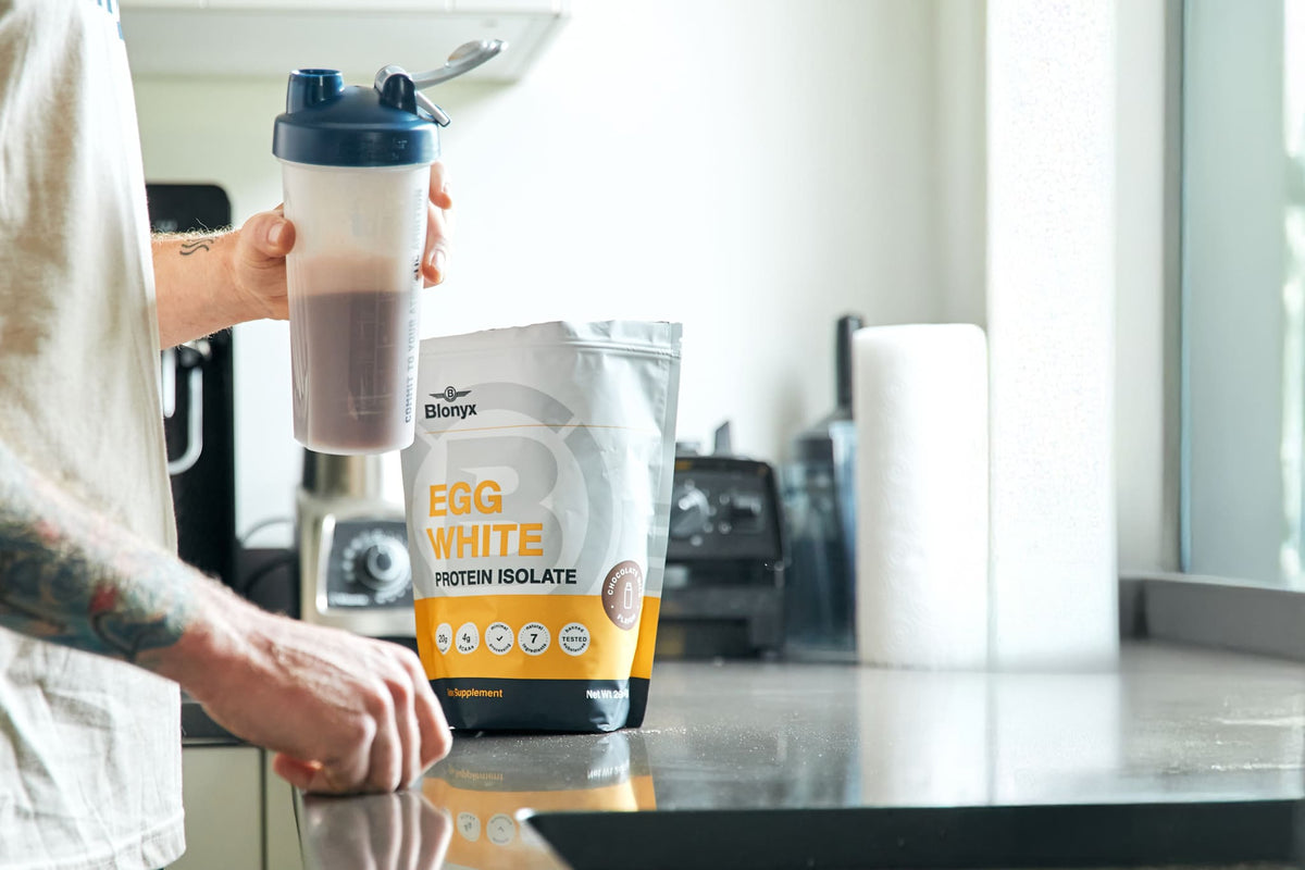 An Athlete in a Kitchen Holding A Shaker with Blonyx Egg White Protein