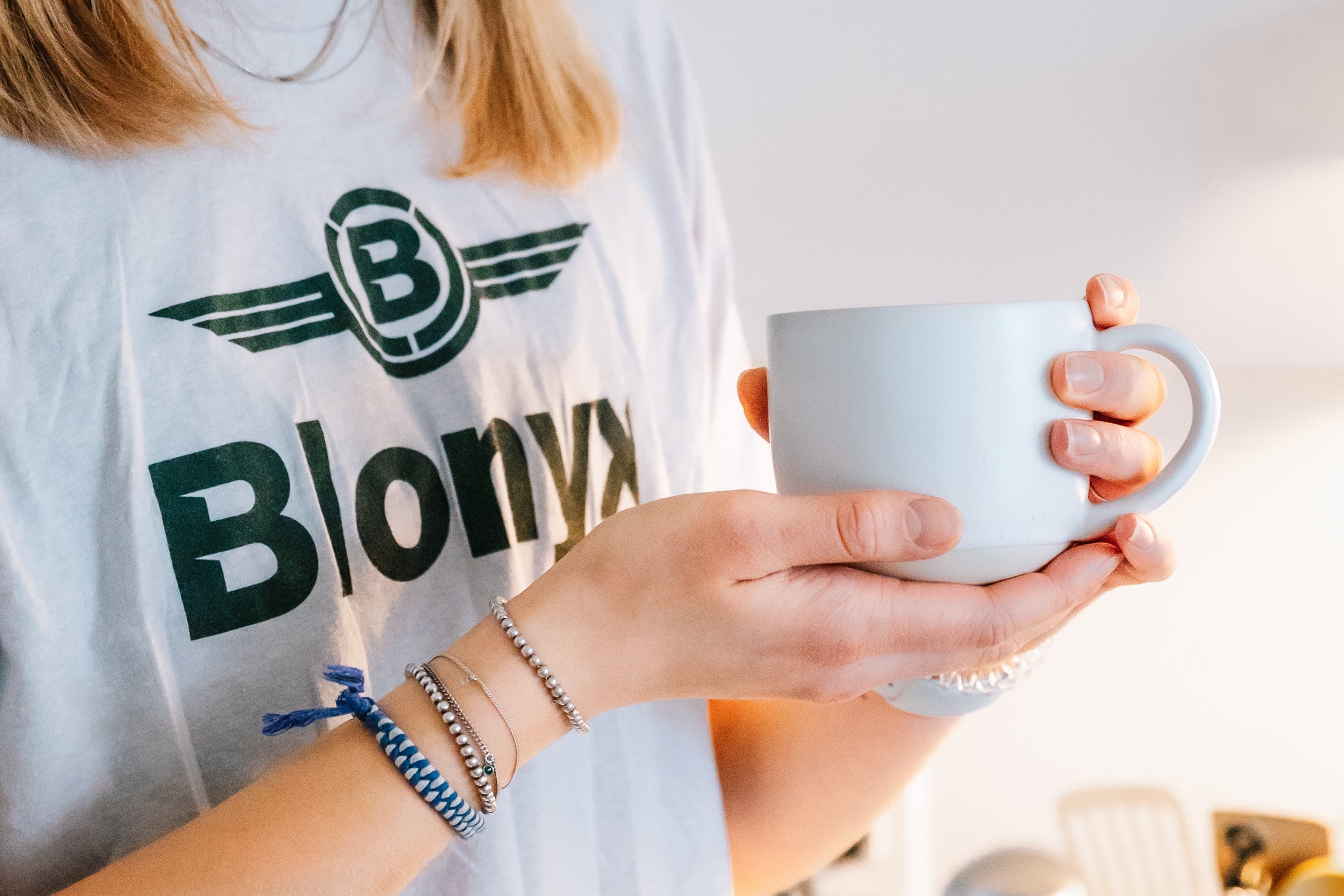 Athlete holding a cup of coffee, wearing a Blonyx tee shirt.