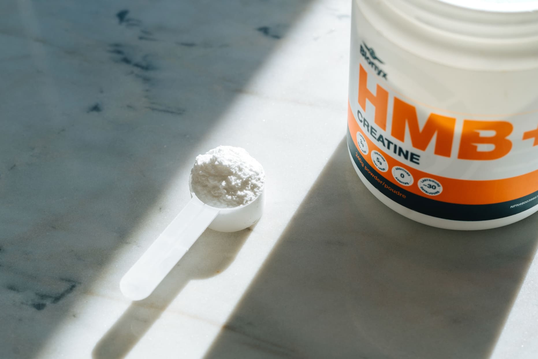 Blonyx HMB+ Creatine powder with a measuring scoop beside the container.