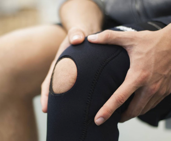 An athlete holding their knee in a brace