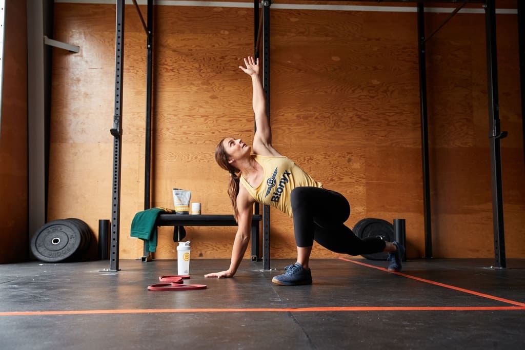 Person stretching in a gym with weights and exercise equipment in the background