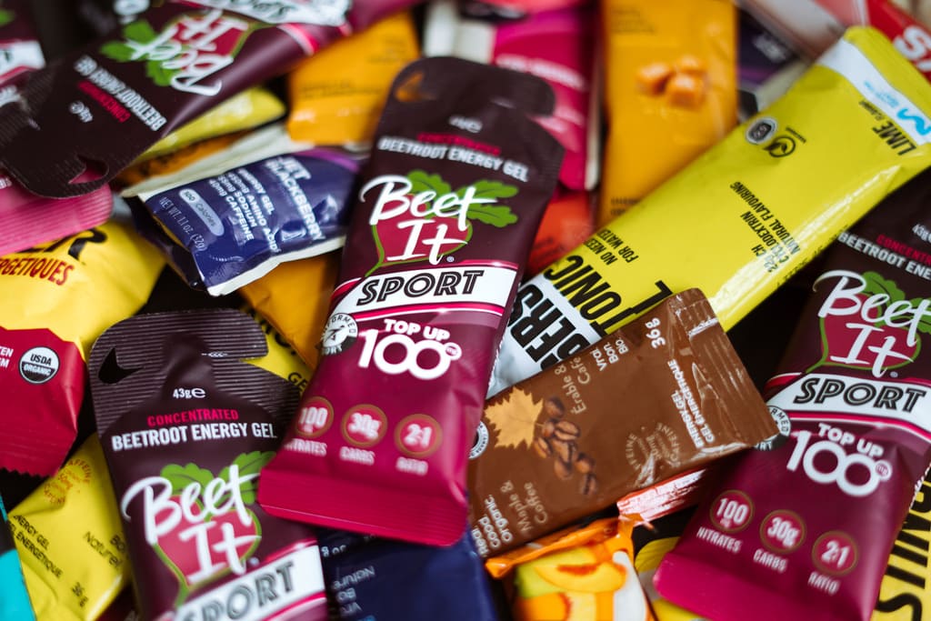 Assortment of endurance nutrition products including Beet It Sport Top Up 100 nitrate energy gels, carbohydrate gels, and sports fuel for training, racing, and recovery.