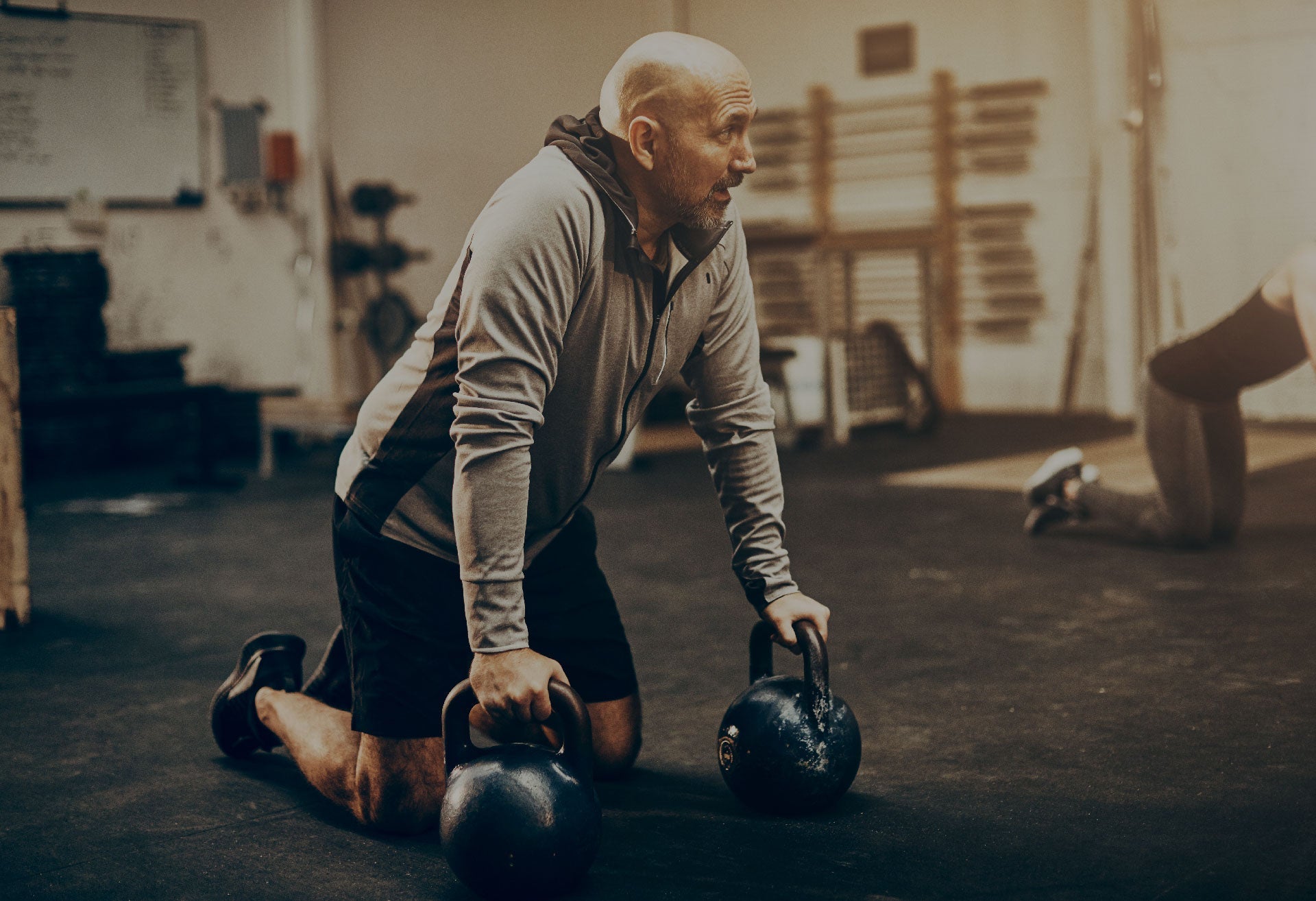 An older athlete holding two kettlebells