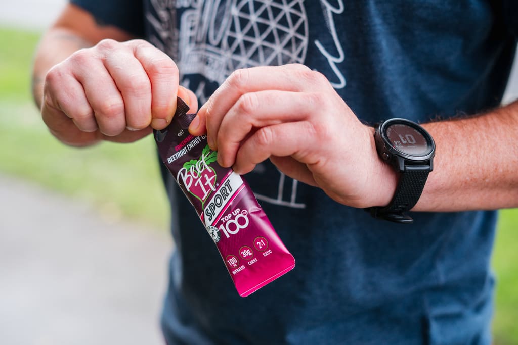 Athlete tearing open a Beet It Sport Top Up 100 energy gel