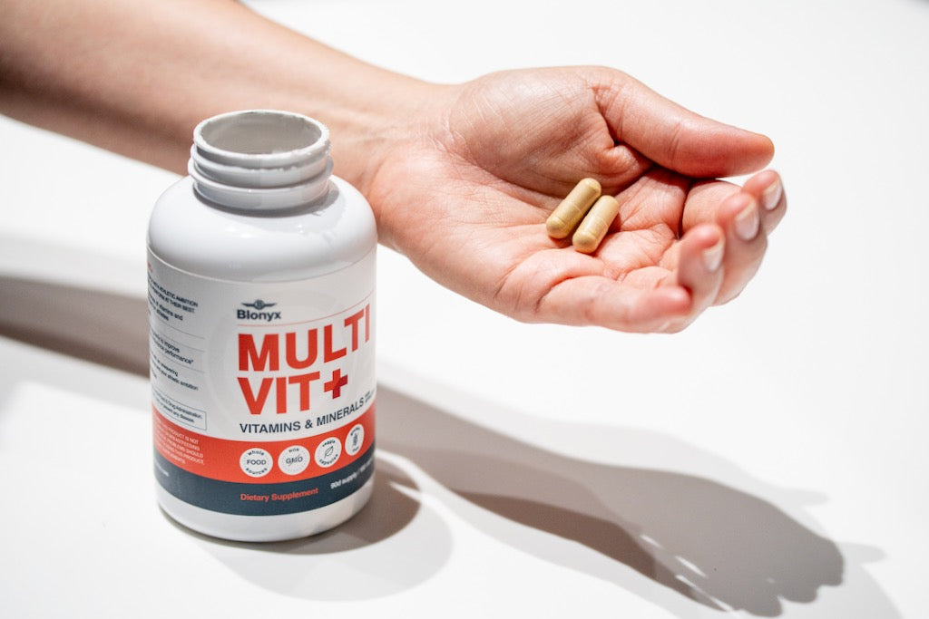 A person holding 2 capsules of Blonyx Multivit+