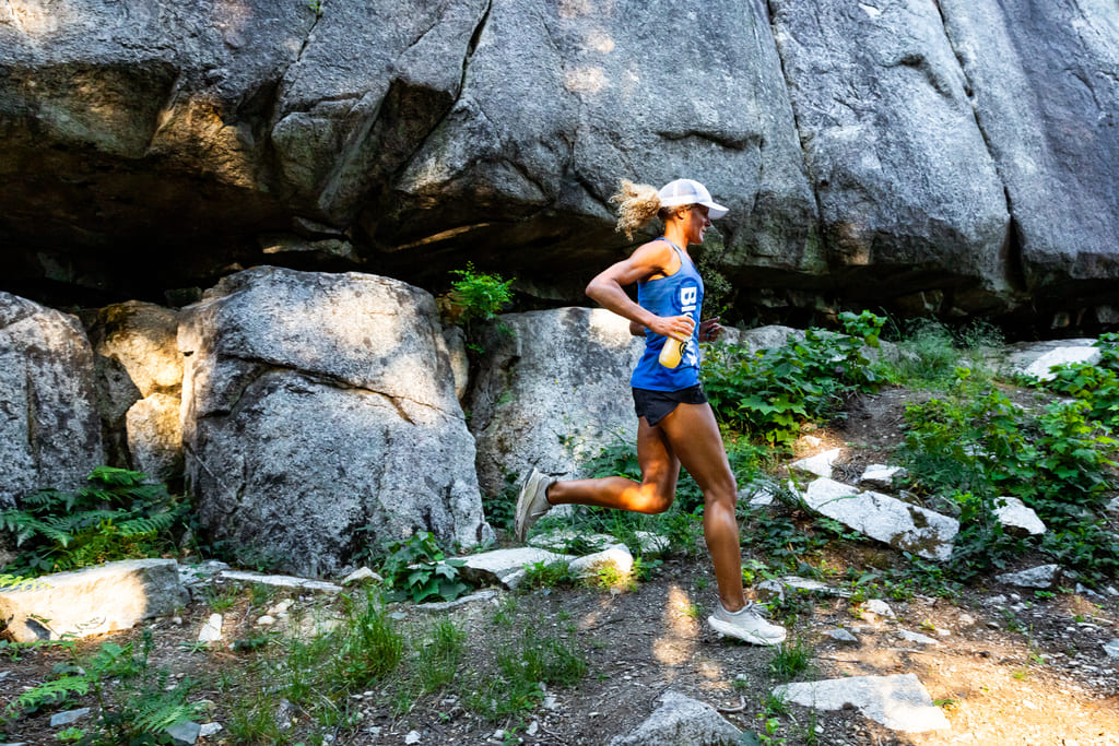 A trail runner in front of a rock face.
