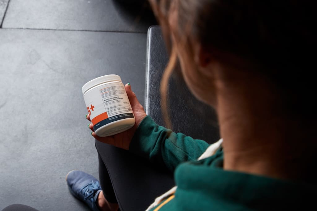 An athlete holding a tub of Blonyx HMB+ Creatine