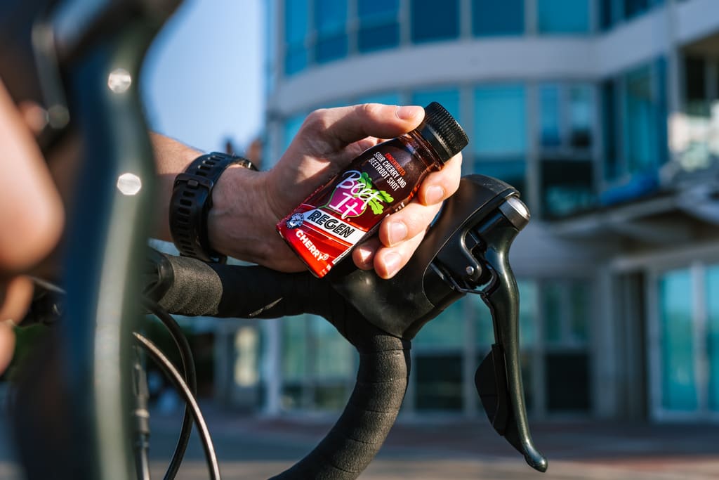 A cyclist holding a Beet It Regen Cherry+ shot.