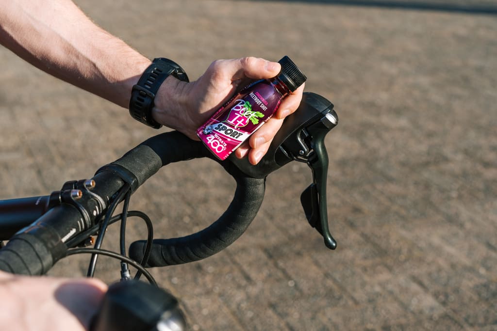 Cyclist Holding Beet It Sport Nitrate 400 on a Bike