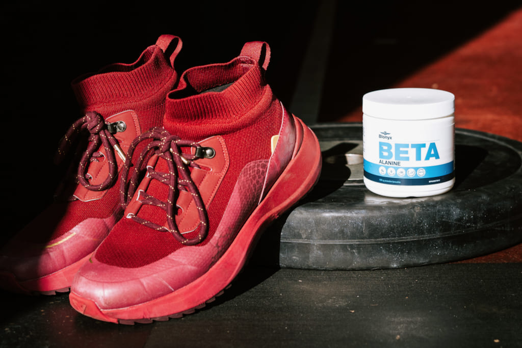Blonyx Beta Alanine supplement beside red training shoes in a gym, supporting muscle endurance, training intensity, and fatigue resistance for athletes and active individuals.