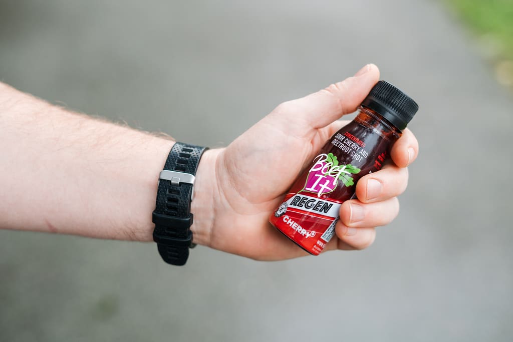 Hand Holding a Tart Cherry Juice Shot 