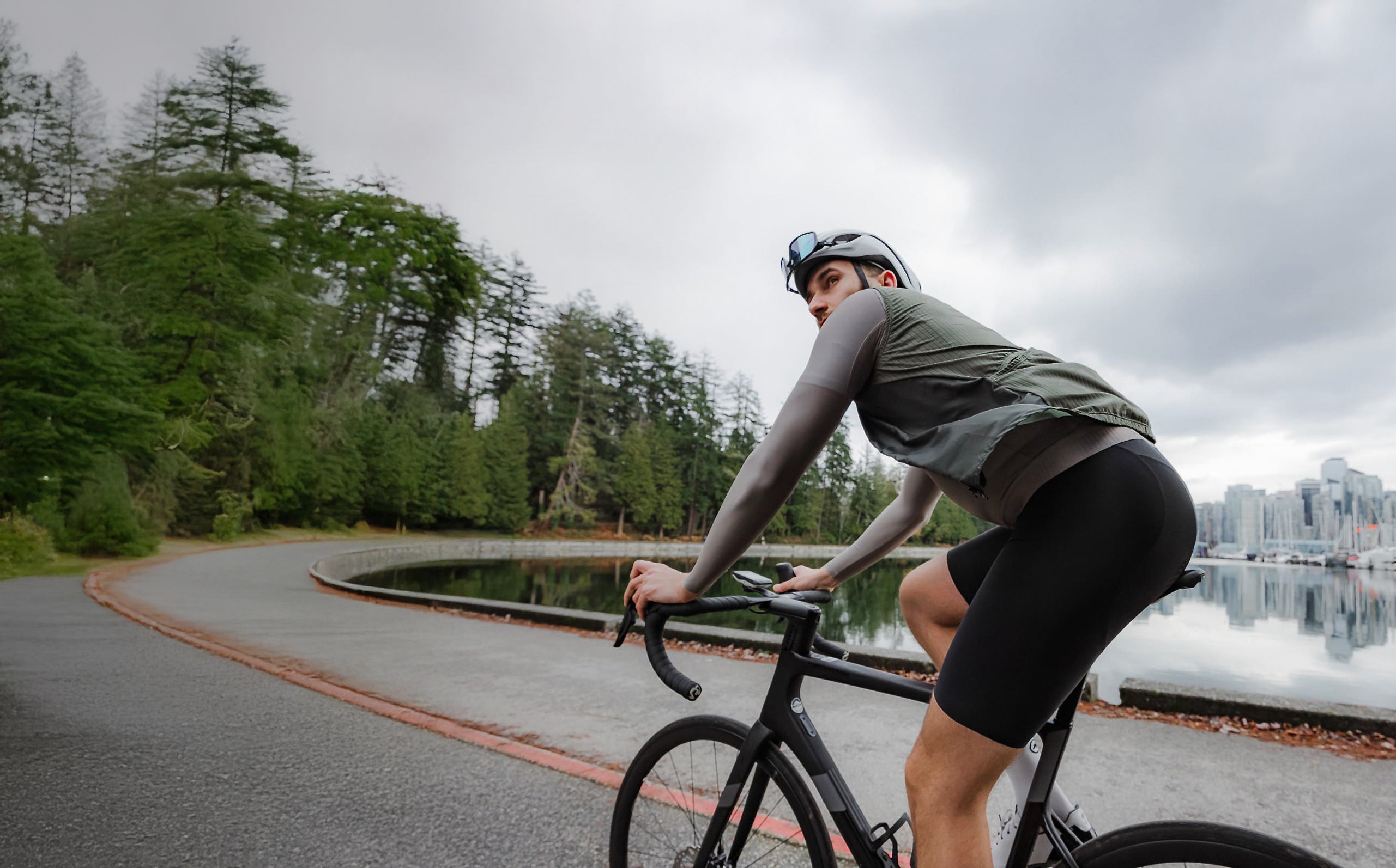A cyclist on a path with the city skyline and water in the background