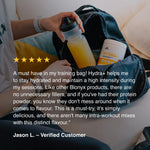 Blonyx Hydra+ energy and electrolyte drink mix beside a cycling water bottle in a training bag, showcasing real-food sports hydration, electrolytes, carbohydrates, and athletic performance support.