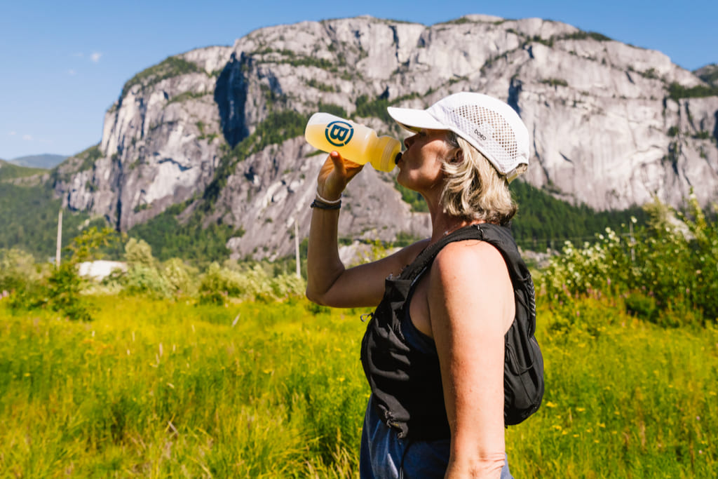 Trail runner drinking Blonyx Hydra+ energy and electrolyte drink in front of mountain scenery, showcasing real-food sports hydration for endurance training and recovery.