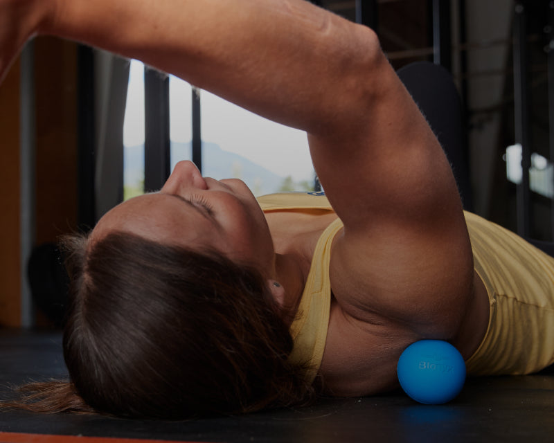 An athlete rolling their shoulder on a lacrosse ball