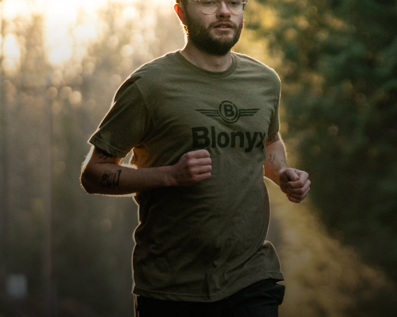 Man running outdoors wearing a green t-shirt with a Blonyx logo.