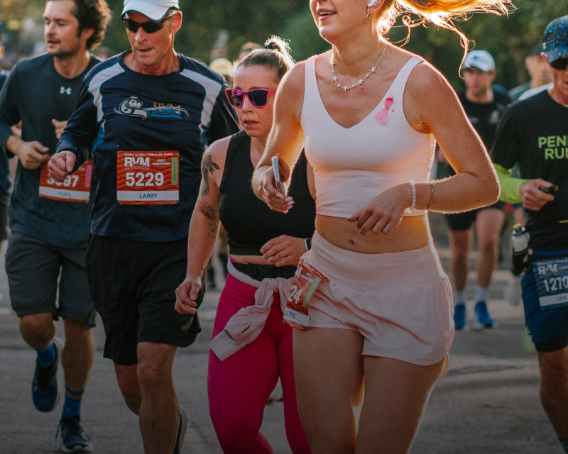 Runners participating in a race with one woman wearing a pink tank top.