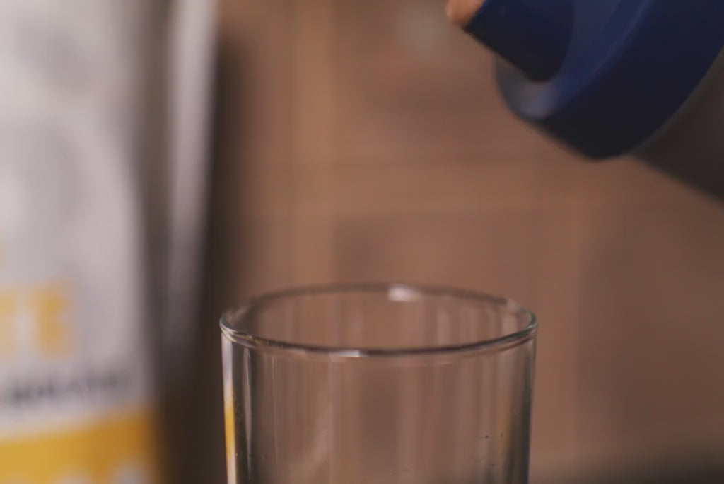 A person pouring Blonyx Egg White Protein Isolate into a glass.